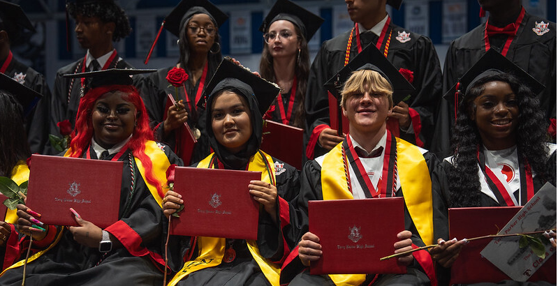 graduates seated and holding their diploma