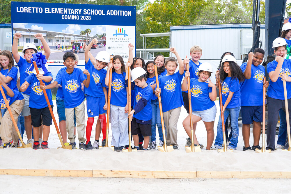 Wide shot of students holding shovels as they pose and celebrate at the groundbreaking ceremony.
