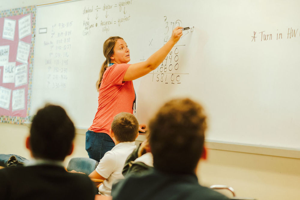 Students watching teacher as she writes on dry erase board