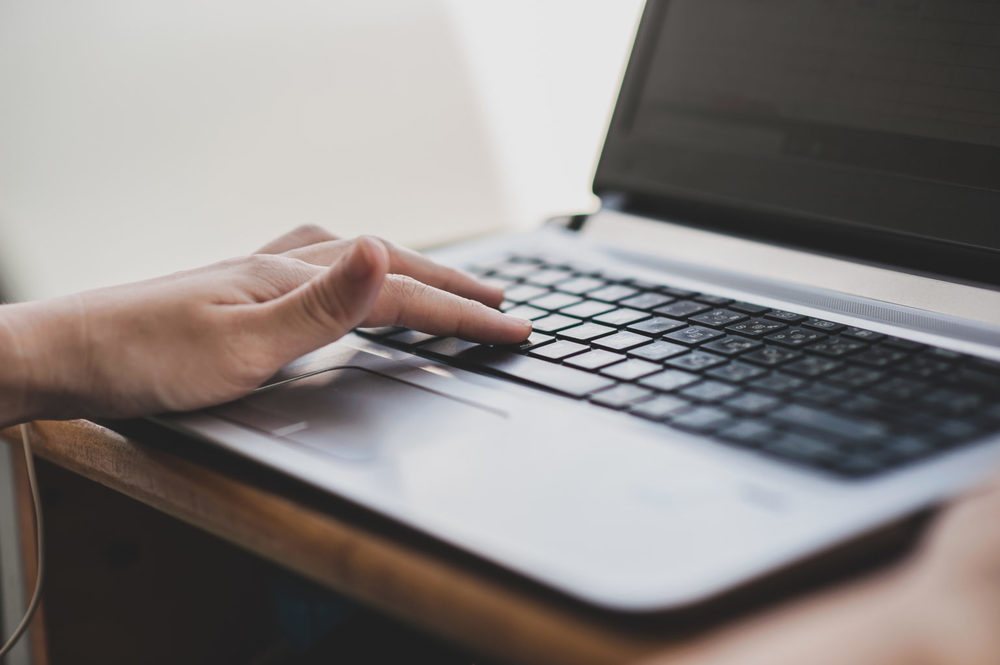 close up of a hand typing on a laptop computer 