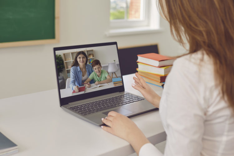 A person using a laptop to video chat with a student and parent. 