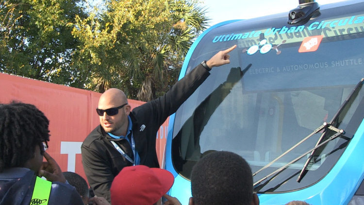 Man, showing students lettering on car windshield