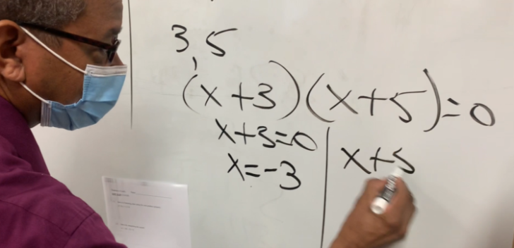 Image of a teacher working out an equation on a white board