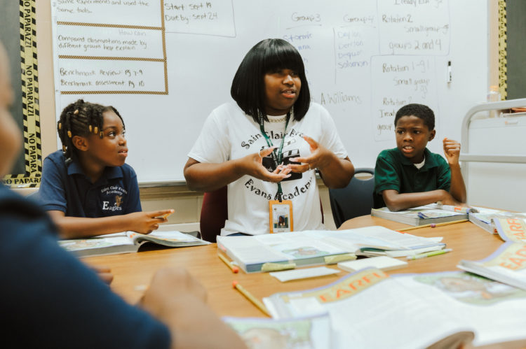 Students and teacher around a table with books open
