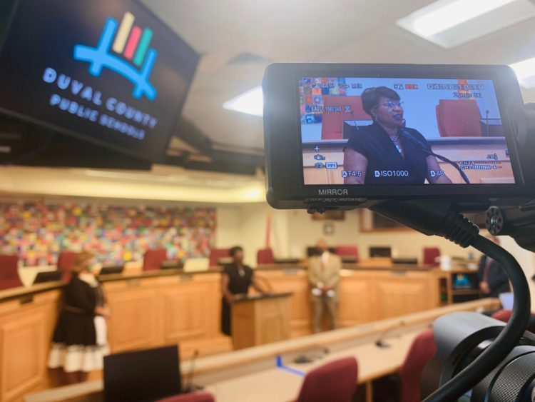 Image of a video camera videoing a woman during a hearing 