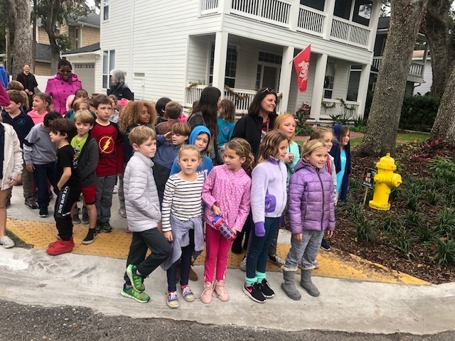 Children walking with teacher on sidewalk