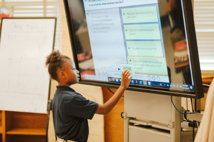 Student stands at screen in class room