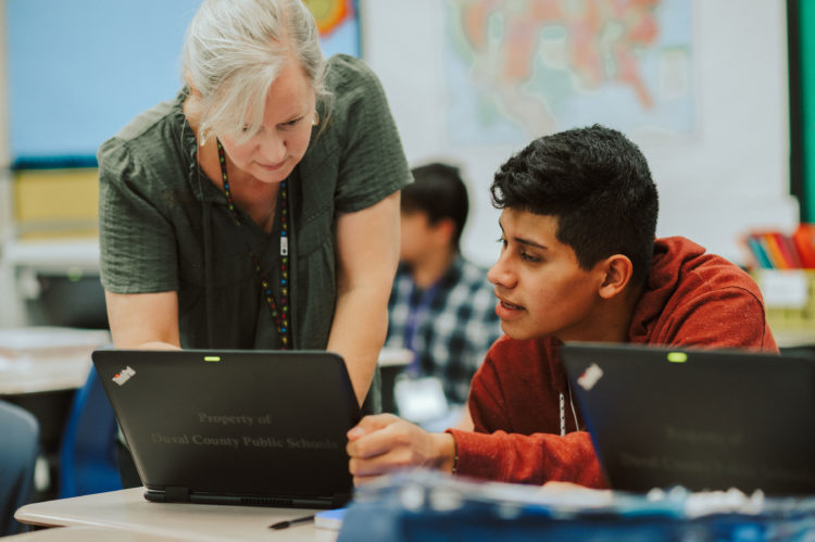 Teacher and student look at a laptop together