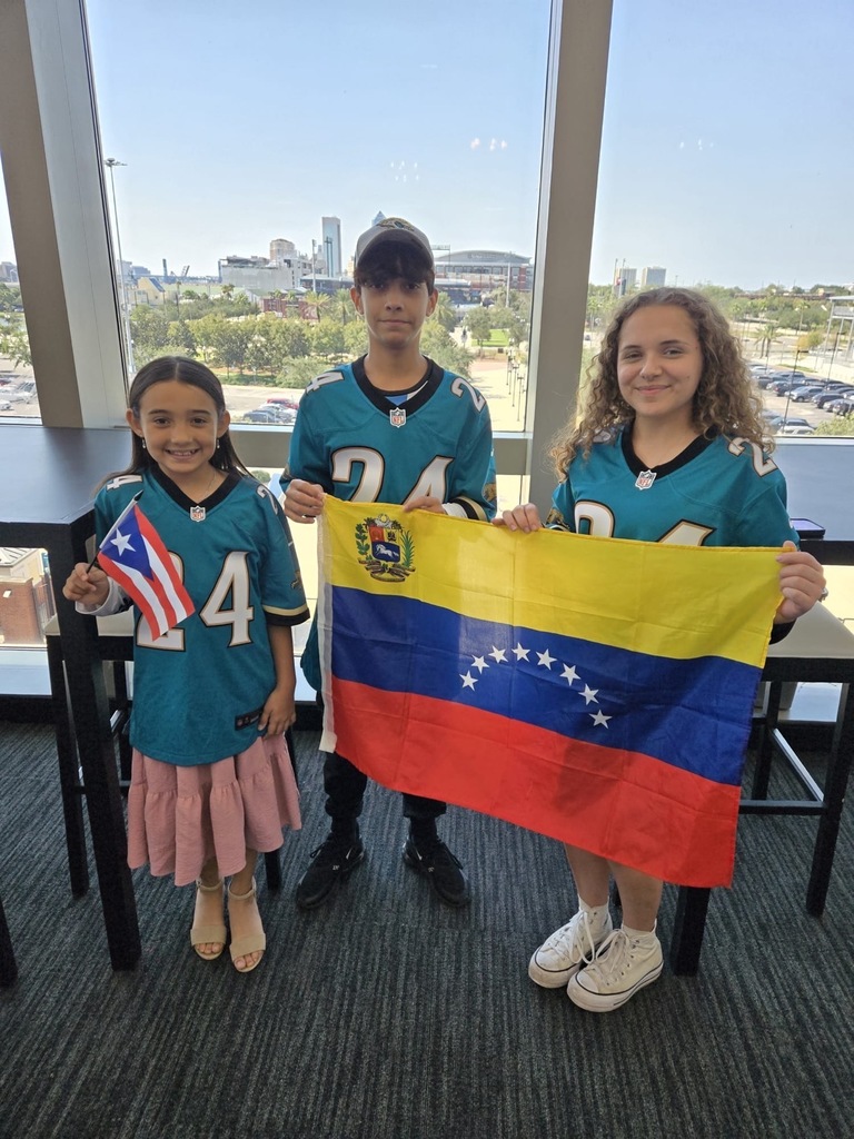 The student winners of last year's essay contest pose with large flags in front of a table.