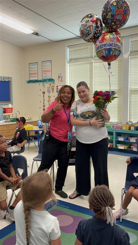 Principal awarding flowers and balloons to teacher of the year