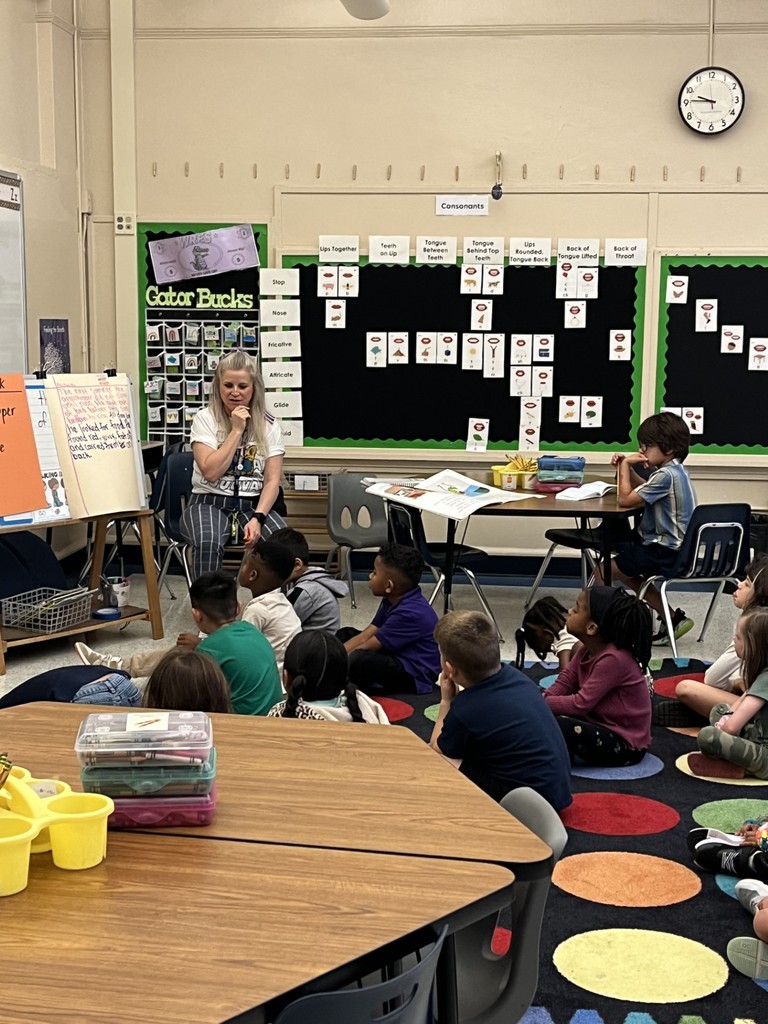 Teacher leading lesson with students watching on the carpet