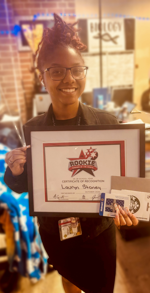 Lauryn Stoney smiles while holding her Rookie Teacher of the Month certificate and gift card.
