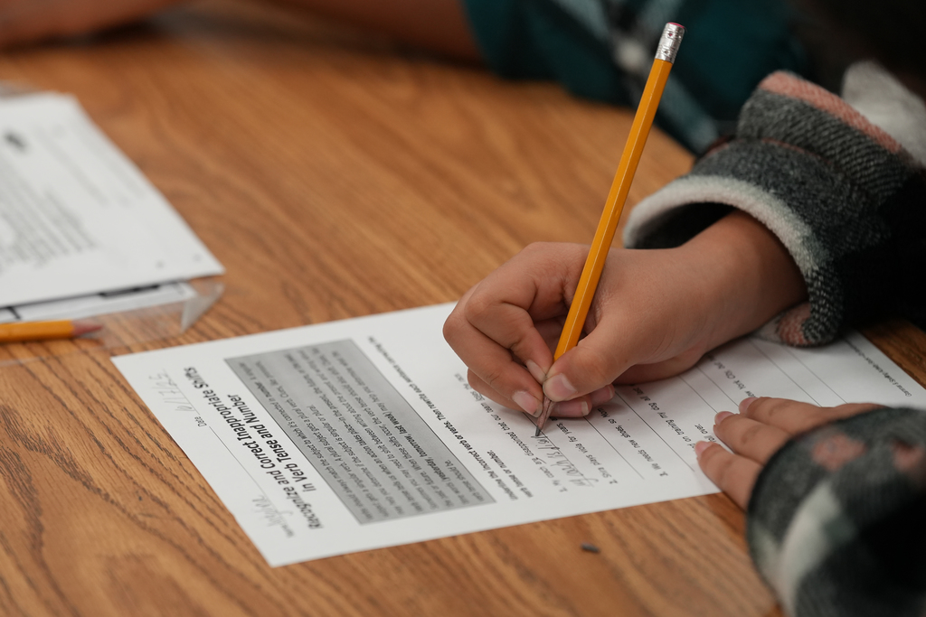 A close-up of students’ hands and notebooks as they write during a class activity in Edina Besic’s room.