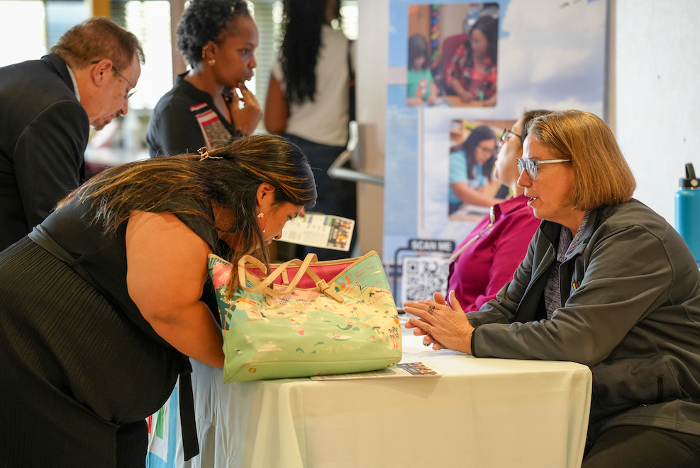  A candidate speaks with a DCPS recruiter at a table during the Retired Educators Hiring Fair, with others meeting in the background.