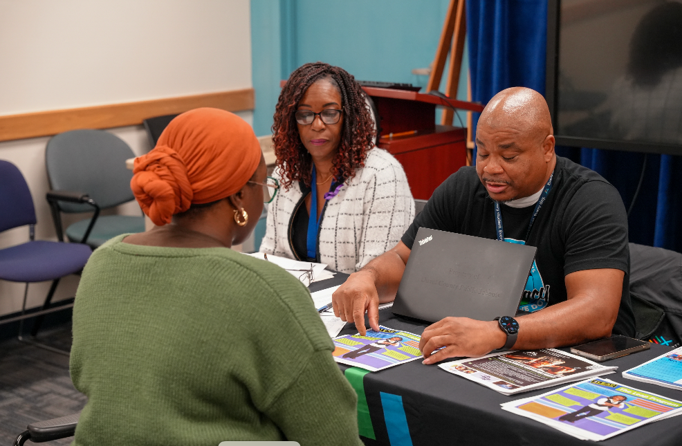  A candidate speaks with a DCPS recruiter at a table during the Retired Educators Hiring Fair, with others meeting in the background.
