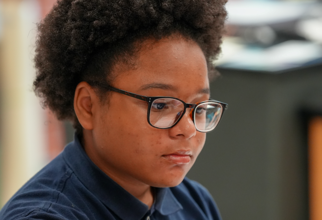 Close-up of a middle school student looking toward the camera while sitting in a science classroom during a lesson.