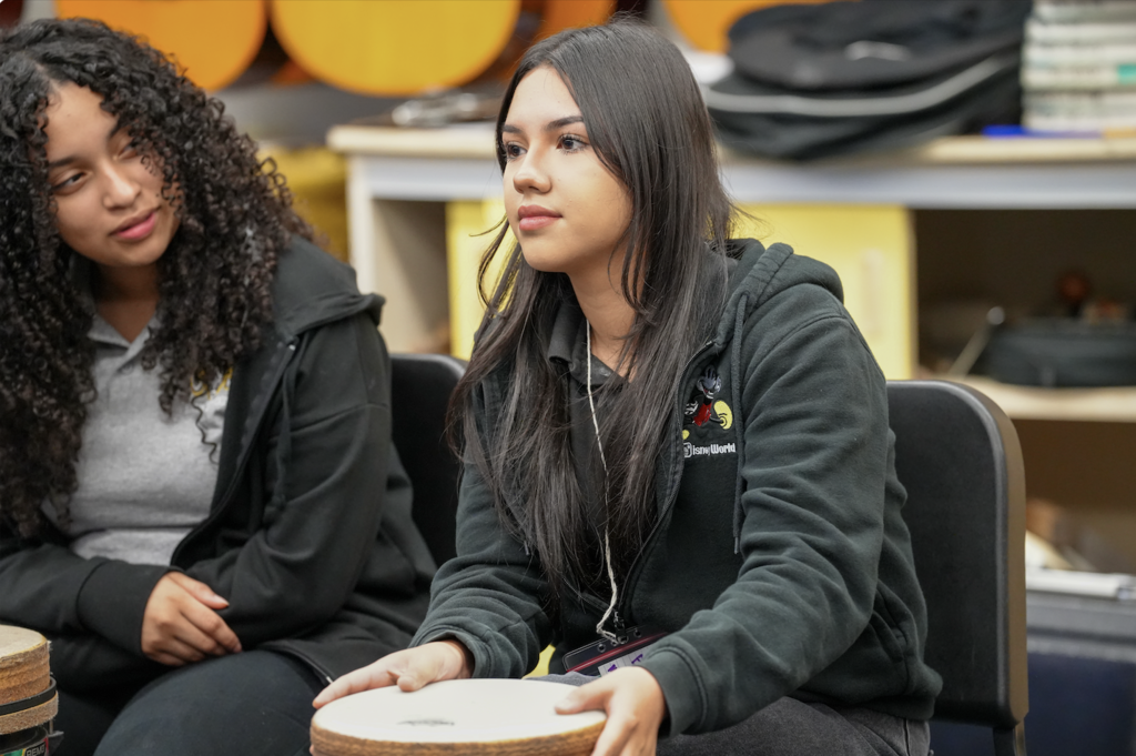 A student plays a hand drum during a music activity at Englewood High School.
