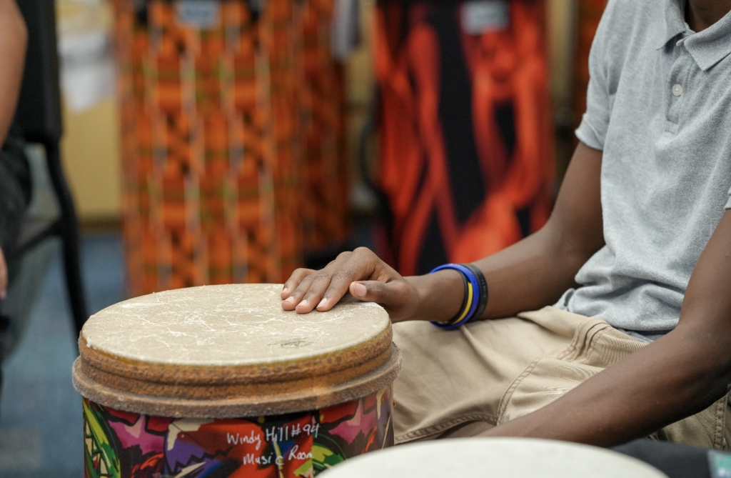A student plays a hand drum during a music activity at Englewood High School.