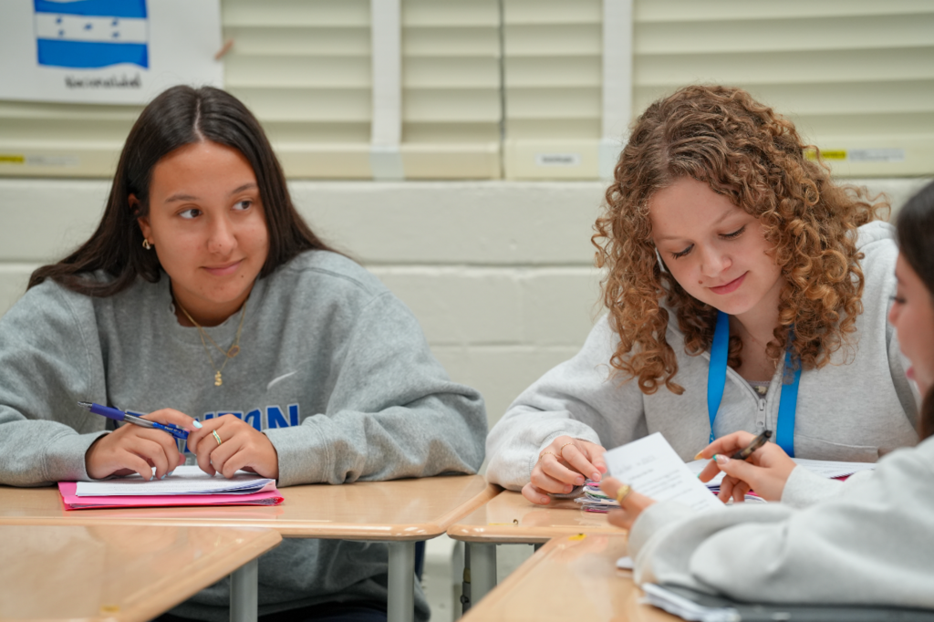 Two students work together at a desk, smiling and collaborating on an assignment during Norma Crespo-Lowery’s Spanish class.