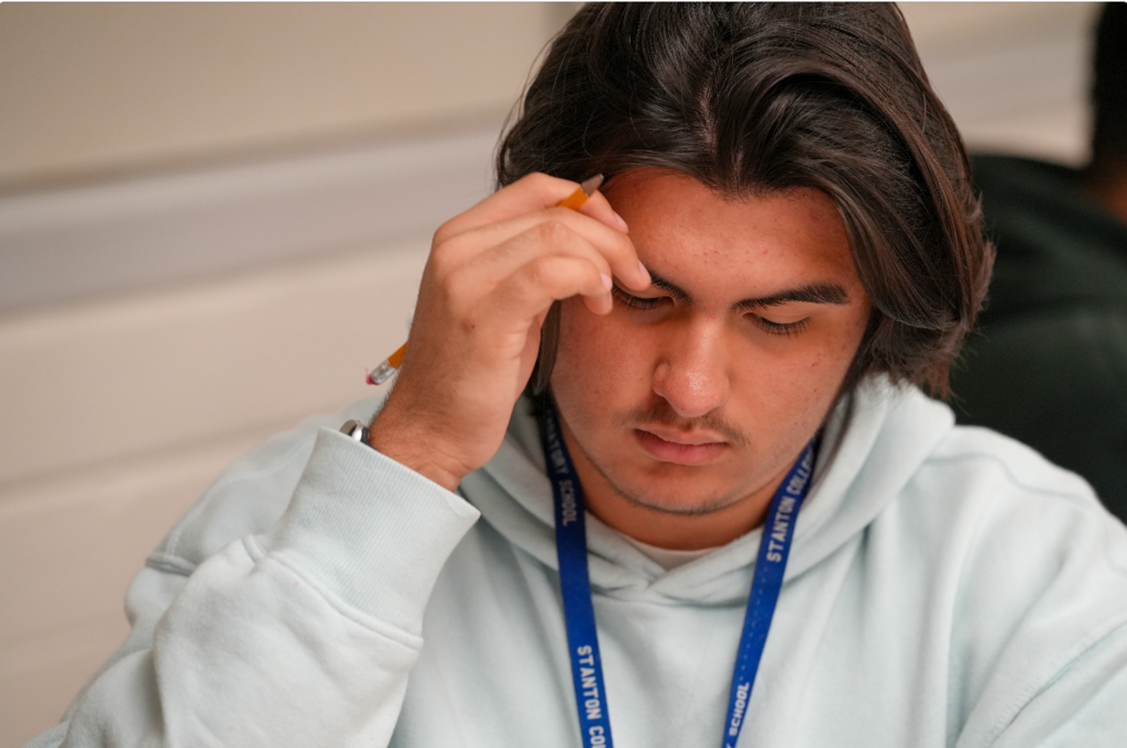 A student focuses on classwork as Norma Crespo-Lowery observes nearby, offering guidance and support in the classroom.