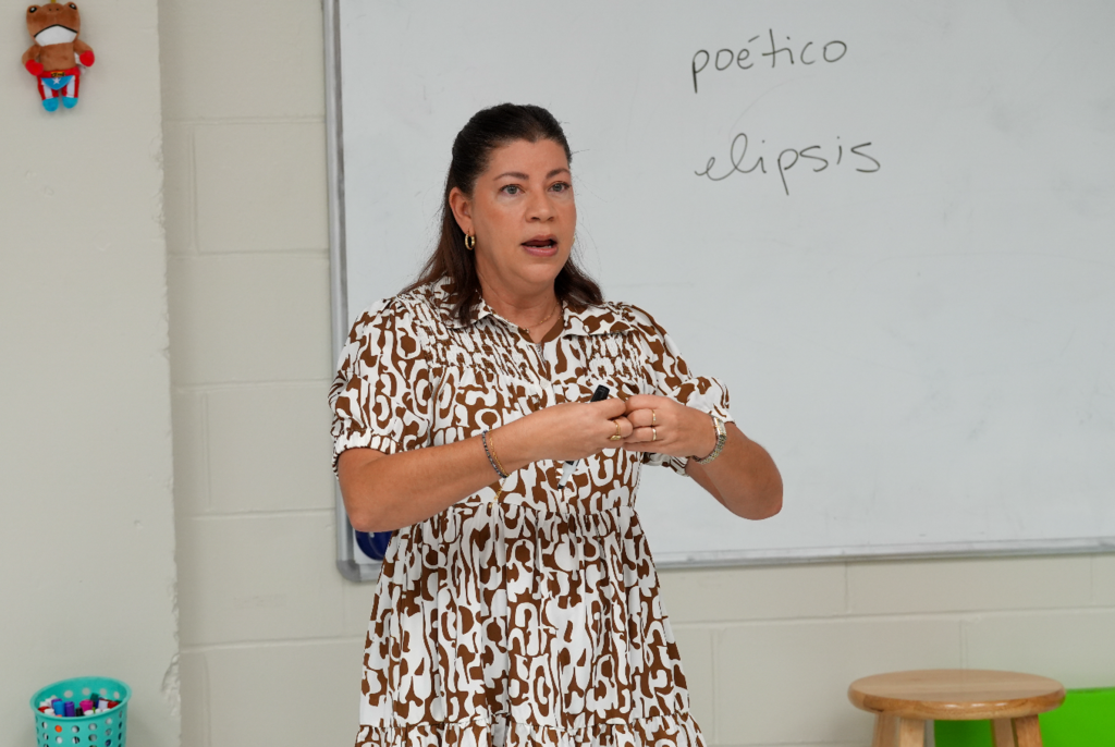Norma Crespo-Lowery listens attentively while a student speaks, creating an engaged and supportive classroom environment.