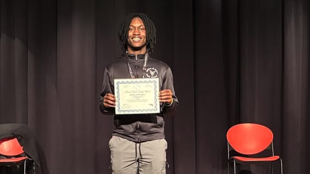 Student Owen poses on stage holding a certificate awarded during the Florida TaxWatch Principal Leadership Awards.