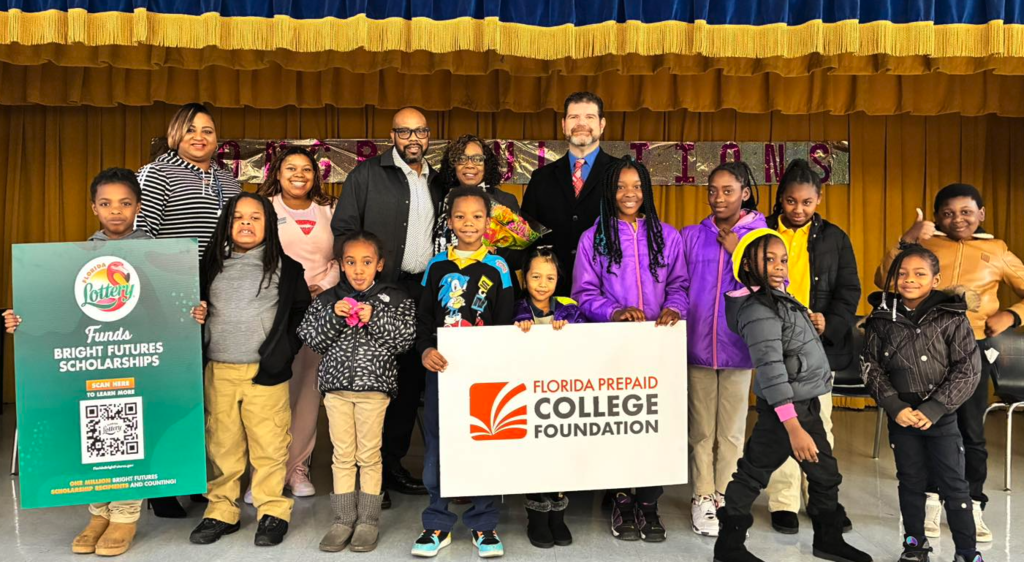 Principal James stands with twin students and staff members on stage at George Washington Carver Elementary School during a Florida TaxWatch recognition event.
