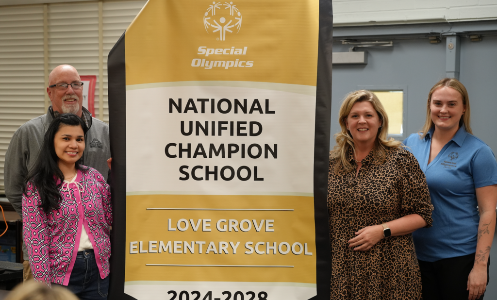 Love Grove Staff stand infront of the National Unified Champion School for Special Olympics.