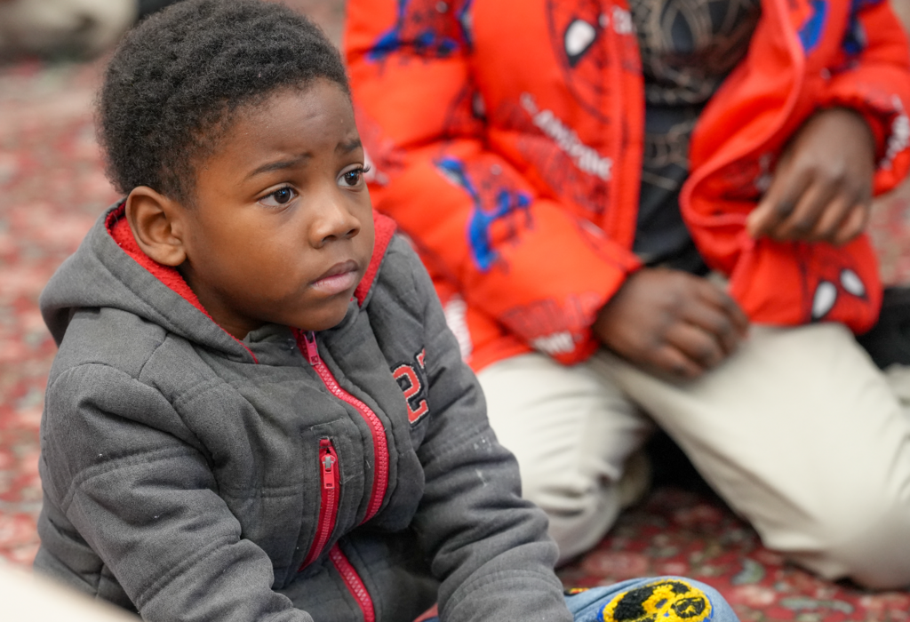 A student sits at a desk listening attentively during a classroom reading session.