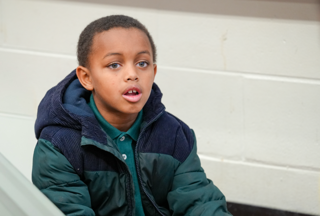 A student sits at a desk listening attentively during a classroom reading session.