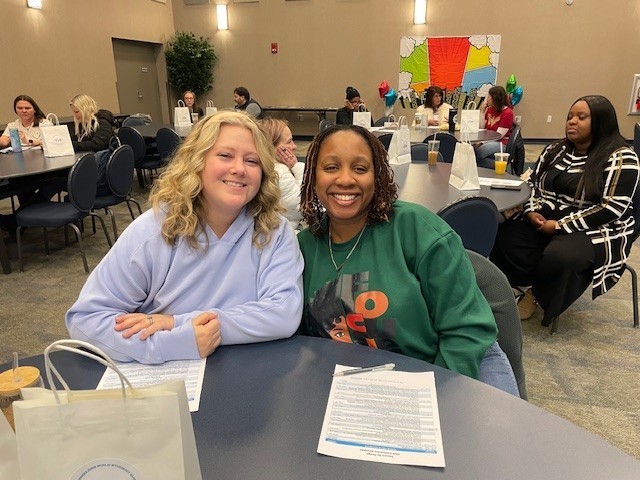 Two counselors smile at the camera as they sit posed together in the Schultz auditorium.