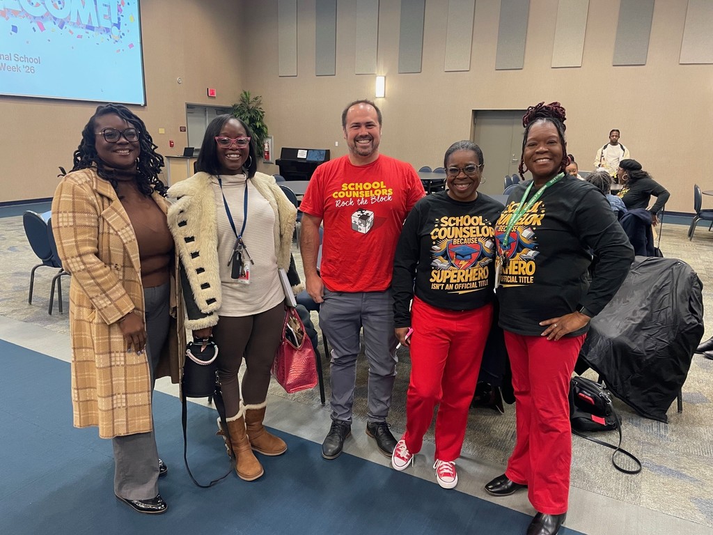 Five counselors stand together in the Schultz Center and smile at the camera