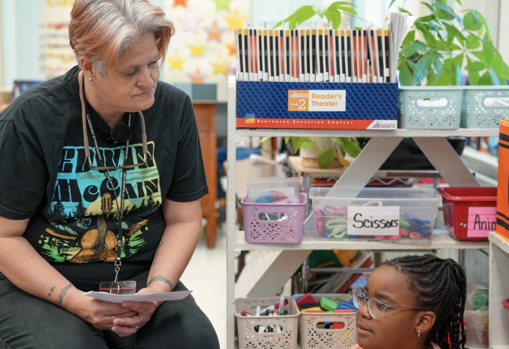 Elizabeth Dent works with a student at a classroom table during a learning activity.