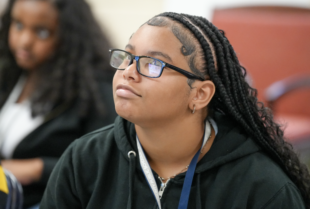 Student with long braids looking upward thoughtfully during a classroom lesson.
