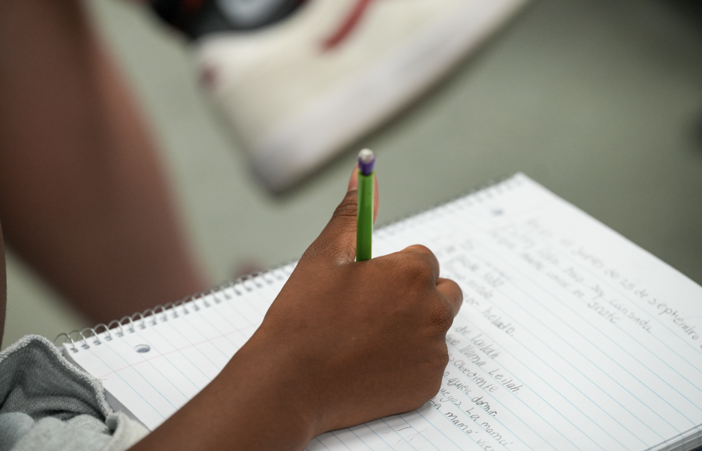 Close-up of a student writing notes with a pencil during Spanish instruction.