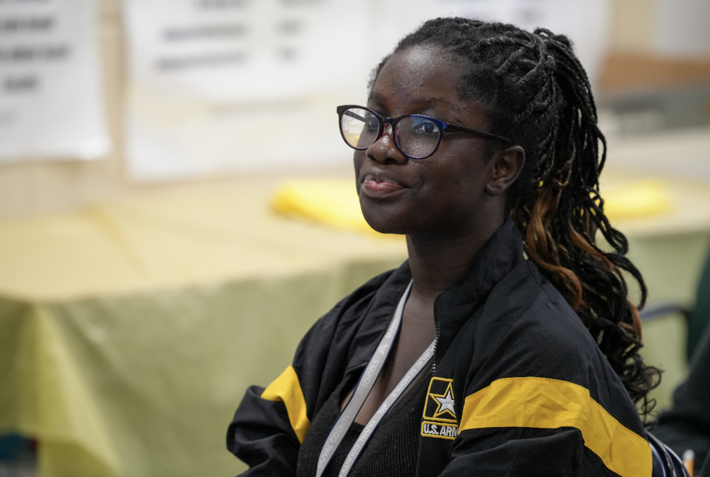 Student wearing glasses looking toward Claudia Elliott during instruction.