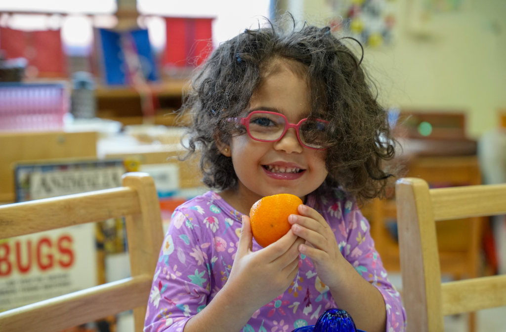 Young Montessori student smiling while working with classroom materials at a table.