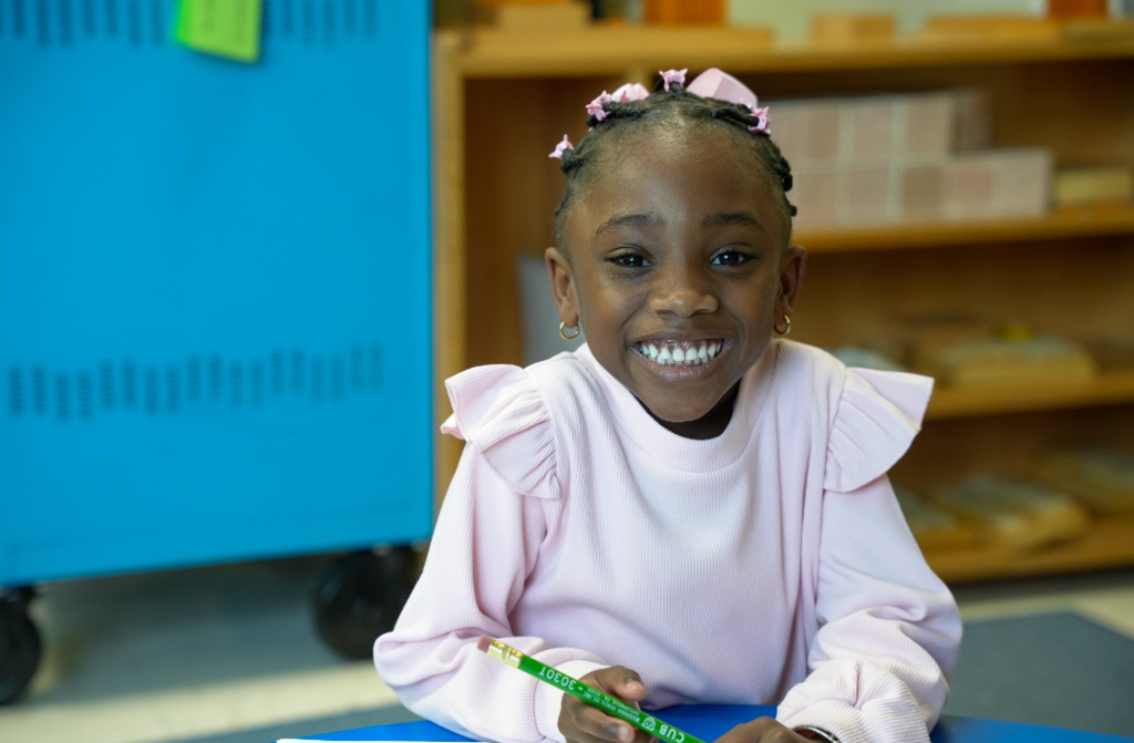 Young student capturing a photo or exploring materials during classroom activity.