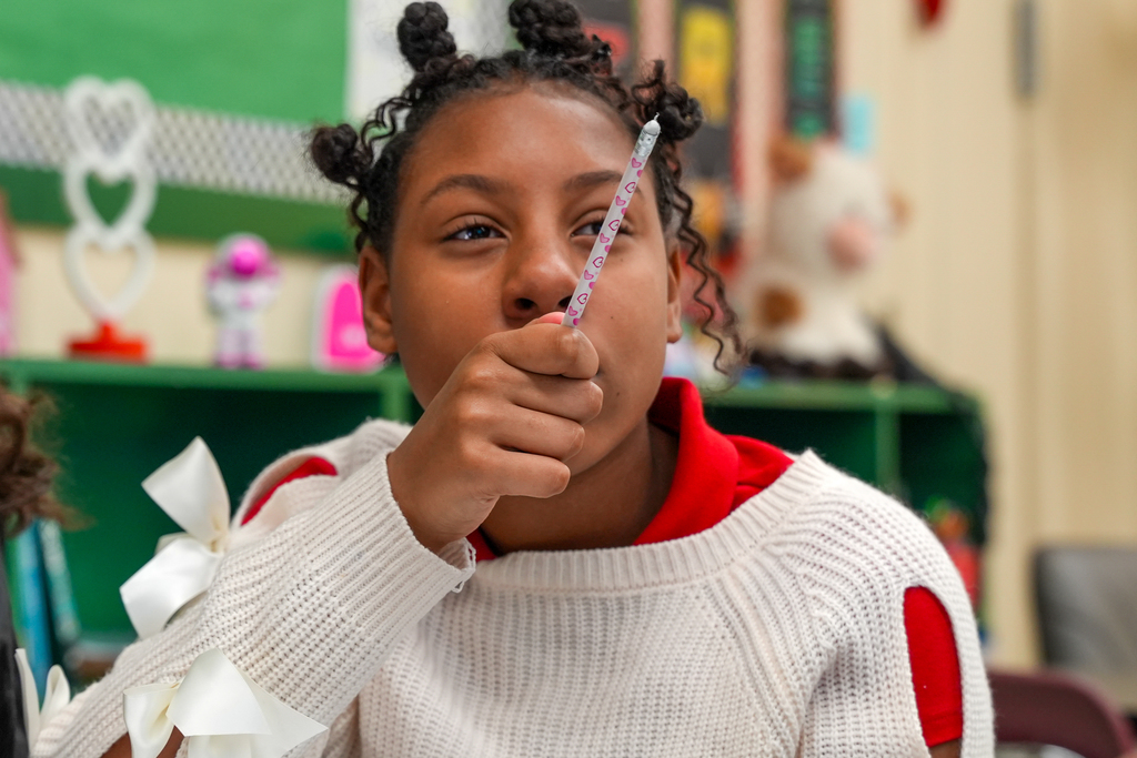 A student holds a pencil upright while thinking through a math problem in Benton Jones’ classroom.