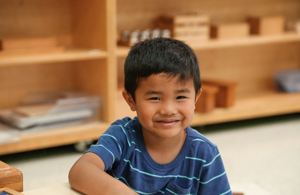A student works quietly with Montessori learning materials on a classroom table.