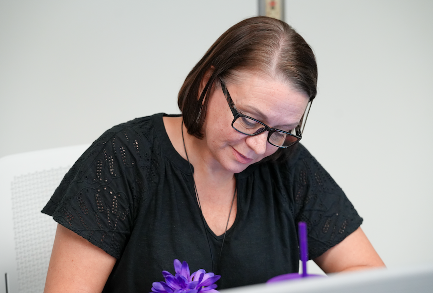 Rebeccah Campbell, Lead Teacher for the Mandarin Academy of Business, assisting students at the credit union workstation.