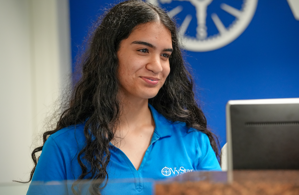 Student in a blue shirt listening during a customer interaction.