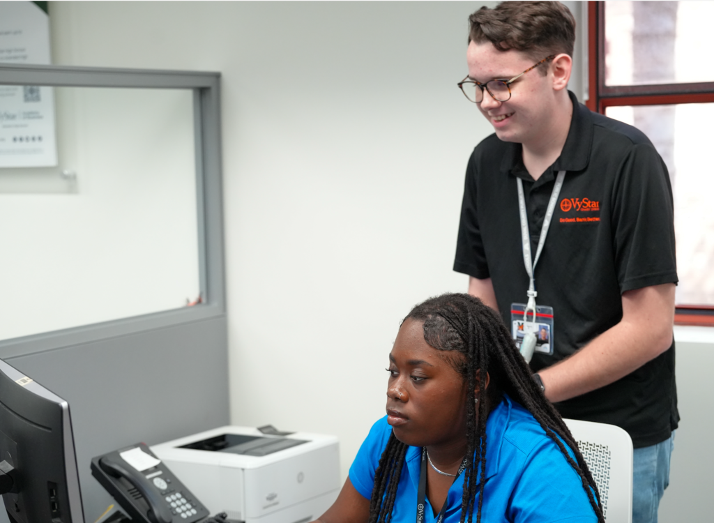 Student helping a peer at the credit union counter.