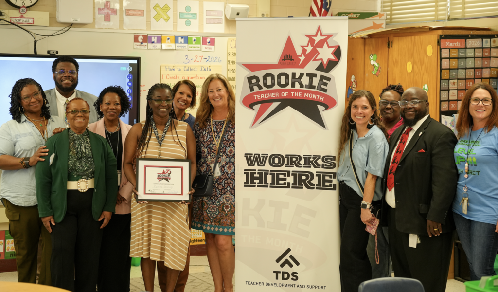 Katrina Jennings stands with school staff, holding her Rookie Teacher of the Month certificate during a recognition moment.