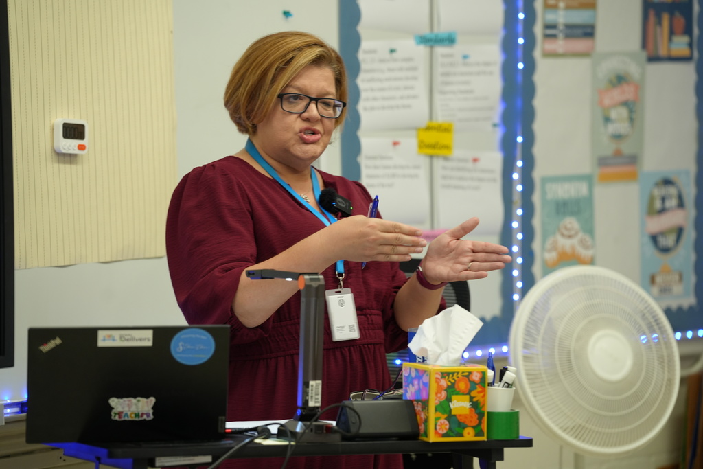 Kelly Klinger, a teacher at Stanton College Preparatory School, stands beside a student and provides guidance while the student works on a laptop in the classroom.