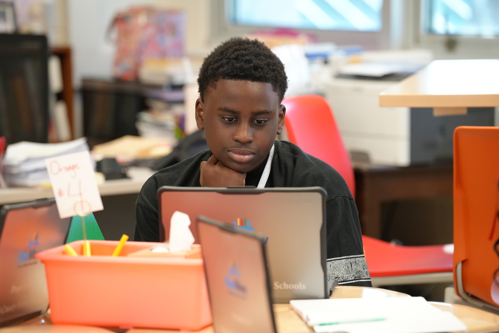 Kelly Klinger, a teacher at Stanton College Preparatory School, stands beside a student and provides guidance while the student works on a laptop in the classroom.