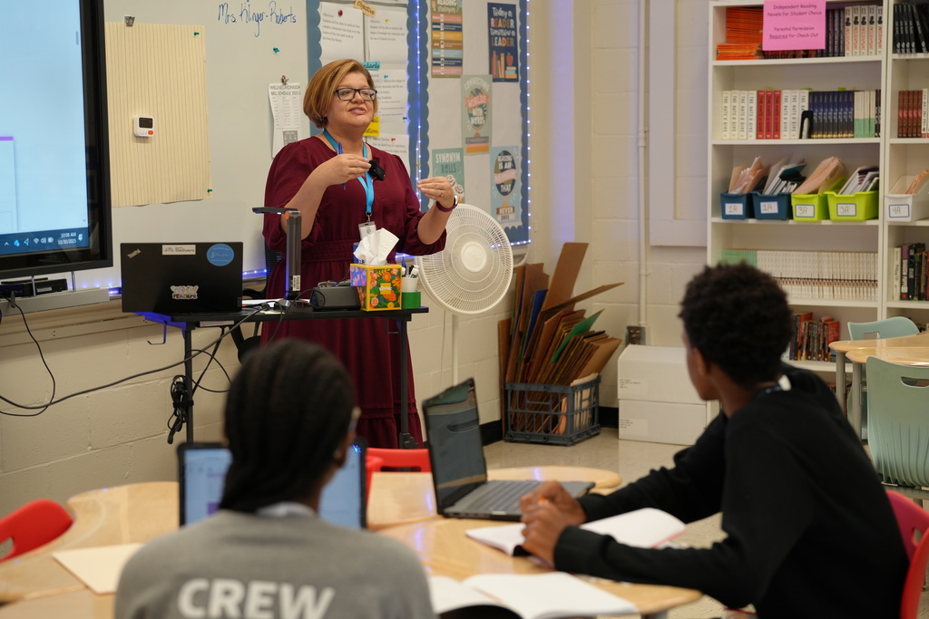 Kelly Klinger, a teacher at Stanton College Preparatory School, stands beside a student and provides guidance while the student works on a laptop in the classroom.
