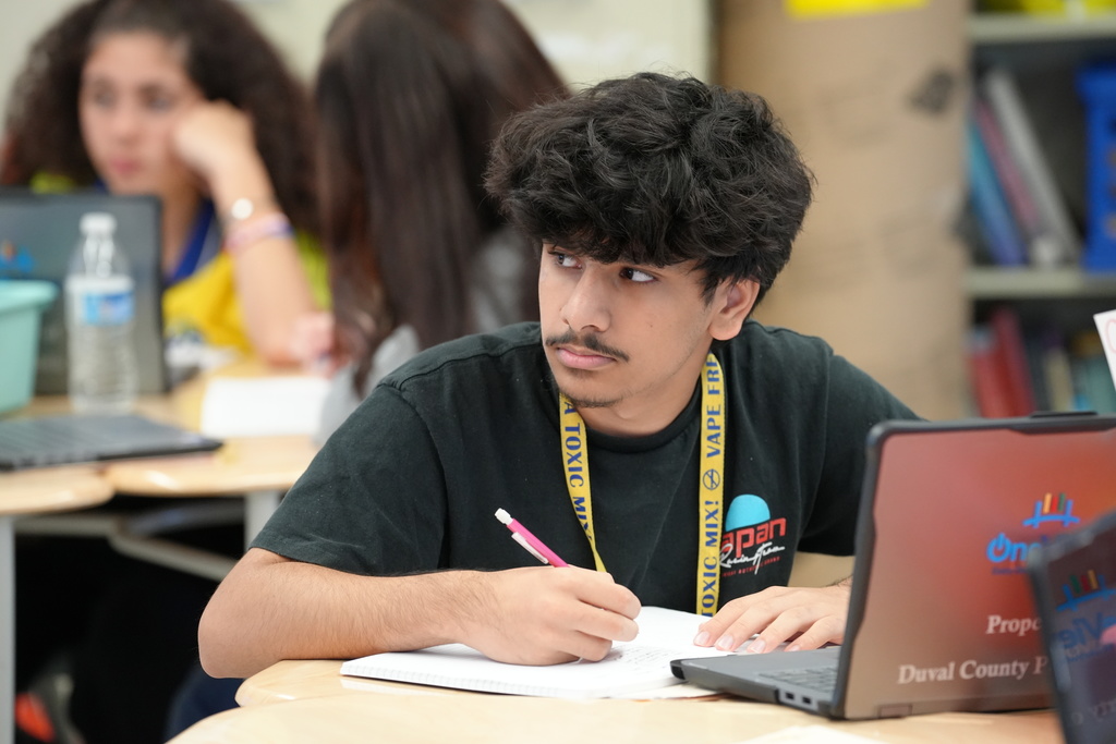 Kelly Klinger, a teacher at Stanton College Preparatory School, stands beside a student and provides guidance while the student works on a laptop in the classroom.