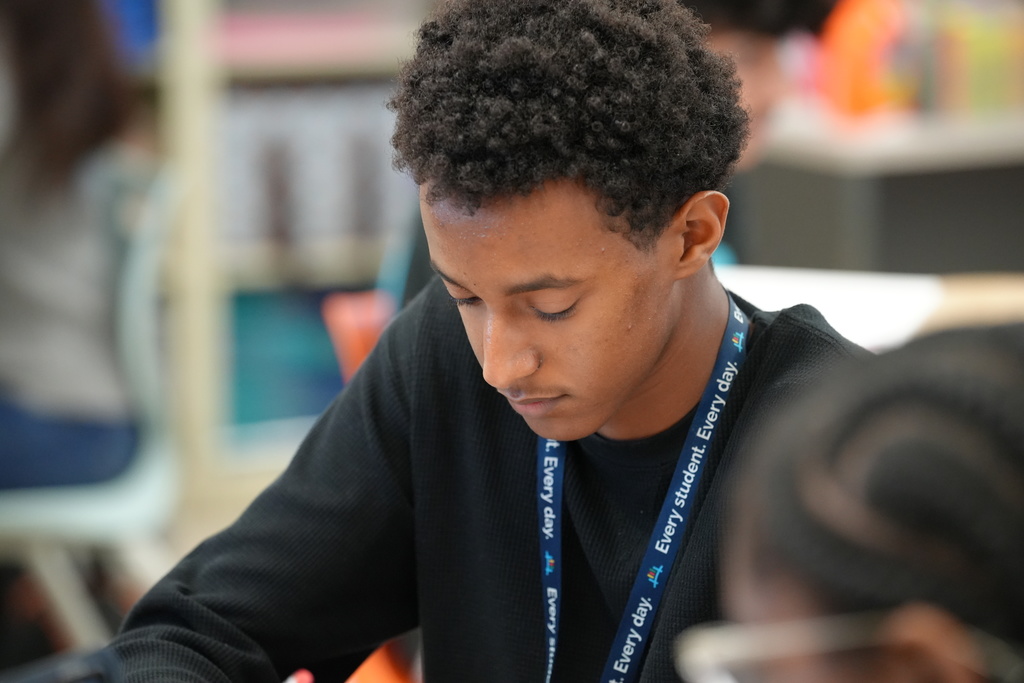 Kelly Klinger, a teacher at Stanton College Preparatory School, stands beside a student and provides guidance while the student works on a laptop in the classroom.