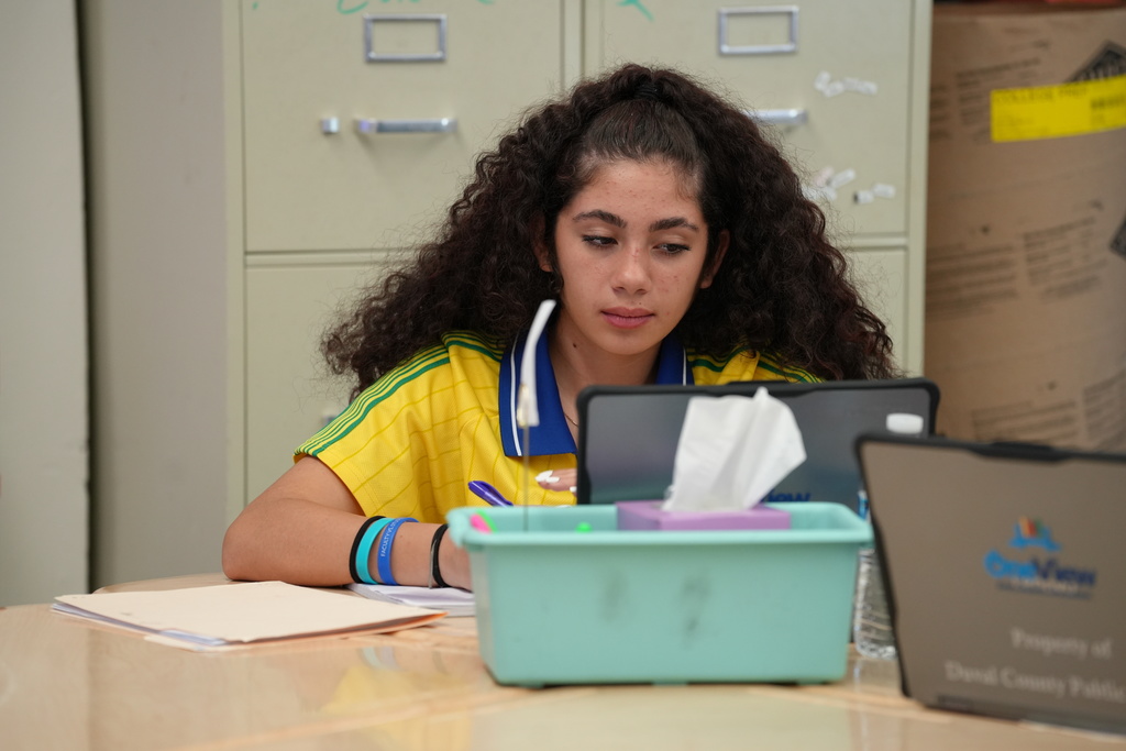 Kelly Klinger, a teacher at Stanton College Preparatory School, stands beside a student and provides guidance while the student works on a laptop in the classroom.